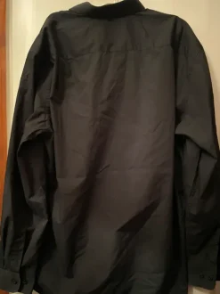 Musta kauluspaita rintataskulla