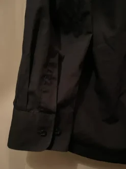 Musta kauluspaita rintataskulla